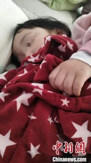 图为闫�h两岁的孩子抱着她的睡衣入睡。　李学晗 摄
