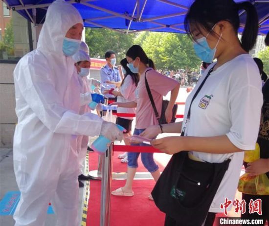 资料图：2020年7月7日，河南郑州，医务人员为进入考点的考生进行体温检查和消毒。河南省卫健委供图