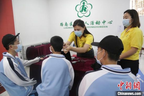 8月30日，耳聋三胞胎在工作人员的帮助下，接受新换上的人工耳蜗声音处理器调试。　施疑 摄