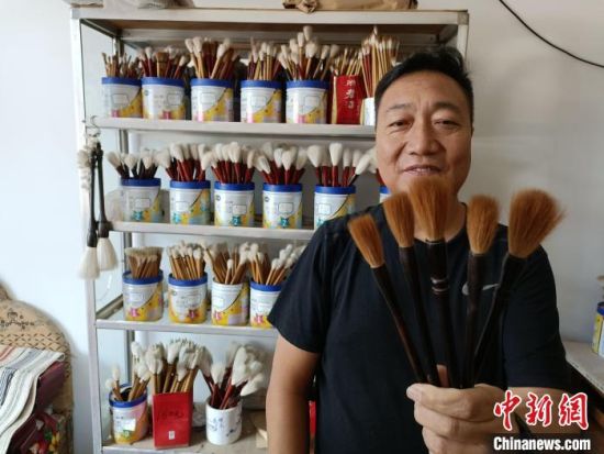 “崔氏毛笔”第三代传承人崔志刚展示手工制作的“狼毫小提”毛笔。　王天译 摄