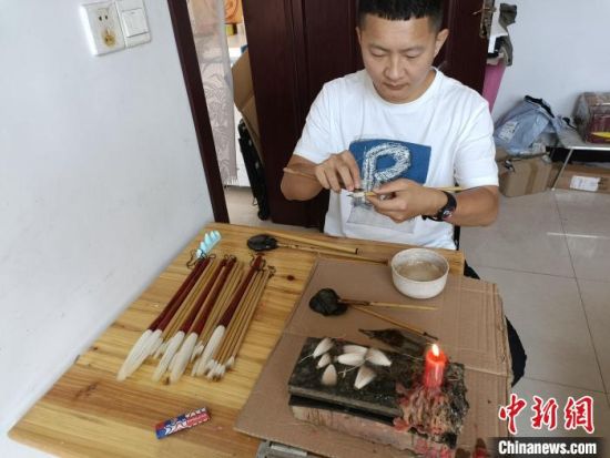 “崔氏毛笔”第四代传人崔大帅在完成制作毛笔的最后一道工序。　王天译 摄