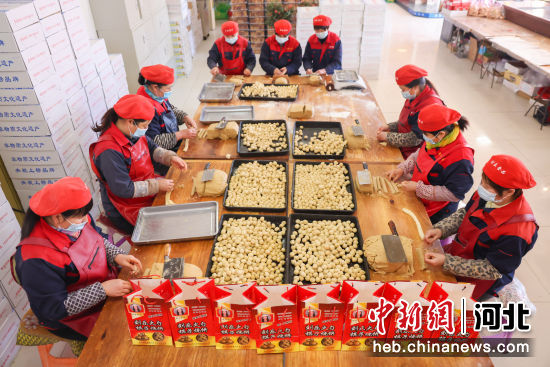 在河北省迁西县三屯营镇传统大集市场上，工人们正忙着制作年货“棋子火烧”。 顾大鹏 摄