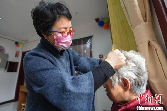 图为邯郸市邯山区志愿者马晓丽义务给老人做头部理疗�！±�� 摄