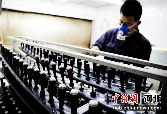 3月25日，在河北省肃宁县一家乐器生产企业喷漆车间，工人正在为乐器上漆。刘巨雷 摄