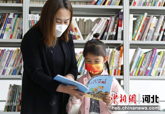 图为在河北省固安县纪家营村寇中天艺术馆图书室，一名小朋友在家长的陪伴下读书。 门丛硕 摄