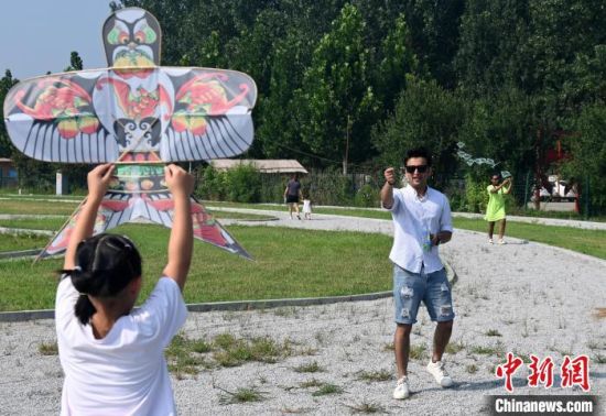 巴基斯坦籍留学生乌玛尔在当地小朋友的帮助下准备放飞风筝�！〉杂鸺� 摄