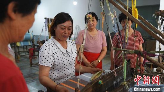 图为张苗芳(左二)现场传授织布技艺。　贾佳贤 摄