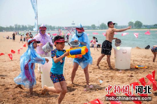 游客在多玛乐园沙滩开启夏日水枪大战。 王川 摄