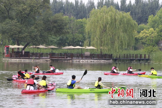 图为永清县林栖谷森林温泉度假区内，游客在湖中体验皮划艇。 作者 刘欣羽