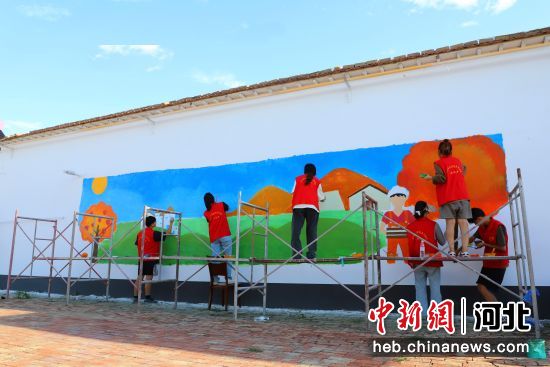 圖為滄州師范學院美術學院的手繪師生和東趙河村新時代文明實踐站的志愿者繪制彩繪墻。 楊洋 攝