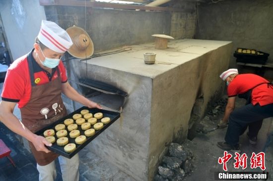 图为9月6日，工人正将月饼送入烤炉。 中新社记者 翟羽佳 摄