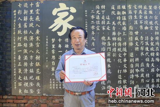 图为青县乡土诗人韩中清在自家“诗墙“前展示获得的《捐赠证书》。 作者 陈兆阳