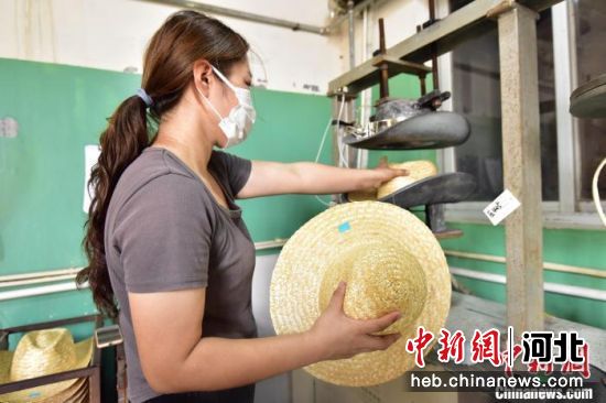 图为青县一家草编工艺品生产企业内，员工将草帽放入模具加热定型。　尹向平 摄