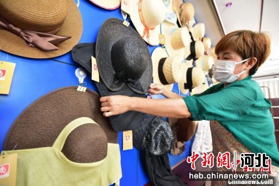 图为青县一家草编工艺品生产企业内，员工打理挂在墙上的工艺品草帽。　尹向平 摄