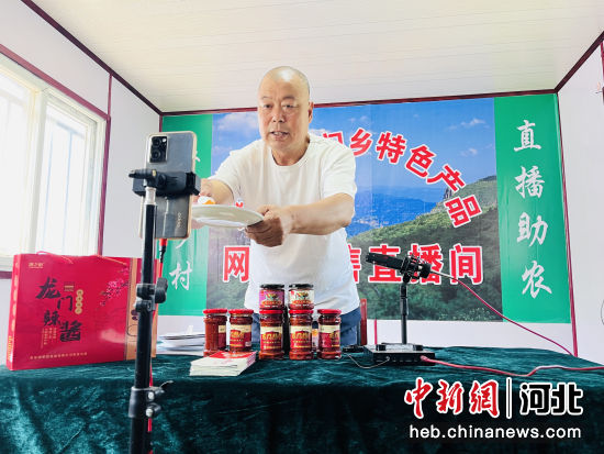图为龙门村党支部副书记通过直播向粉丝推介家乡辣酱。 作者 李金璐