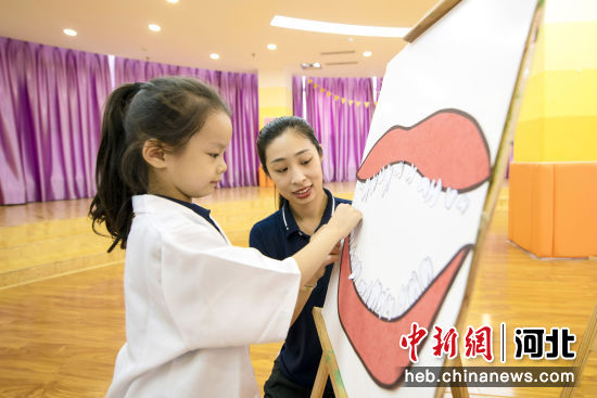 图为廊坊市广阳区爱民东道街道新星里社区，孩子们在老师的指导下完成牙齿贴画。 作者 付瑞琪