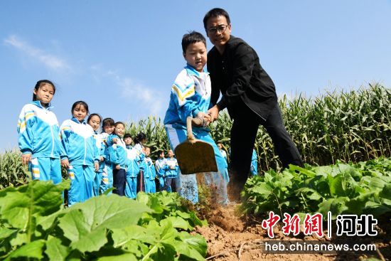 图为广平县胜营镇中心小学劳动课上老师指导学生在田间学习锄草。 作者 程学虎