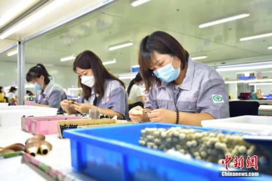 资料图为2022年6月9日，青县某制刷厂生产线上，员工们在对化妆刷进行修型。 中新社发 尹向平 摄