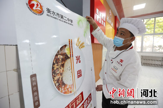 食堂工作人员在摆放“光盘行动”宣传海报。 陈连胜 摄