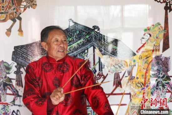 唐山皮影艺人李绍民在家里的墙上耍皮影。　朱大勇 摄