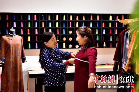 在河北省隆尧县北楼乡一家服装加工企业，旗袍裁缝师(左一)为顾客量体。 作者 潘志方