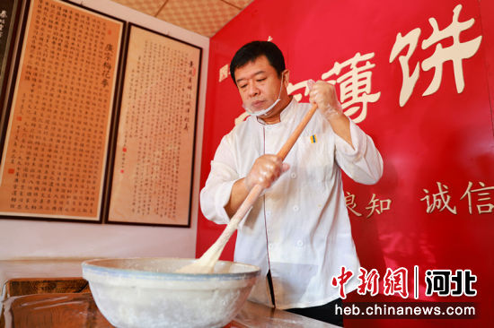 广宗薄饼制作技艺传承人卫桂卿在使用面杖搅面。 作者 梁智晓