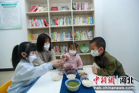 在滦州市滦河街道冀东人家社区多功能活动室，志愿者给孩子们讲解制作腊八粥所需食材。 李阳 