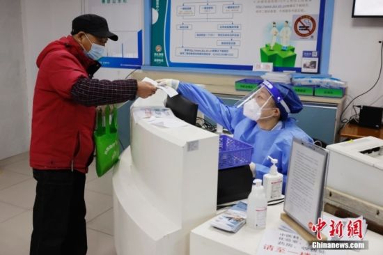 1月1日，在上海市长宁区程家桥街道社区卫生服务中心的发热哨点，医护人员为前来就诊的市民进行预检、挂号。 中新社记者 殷立勤 摄