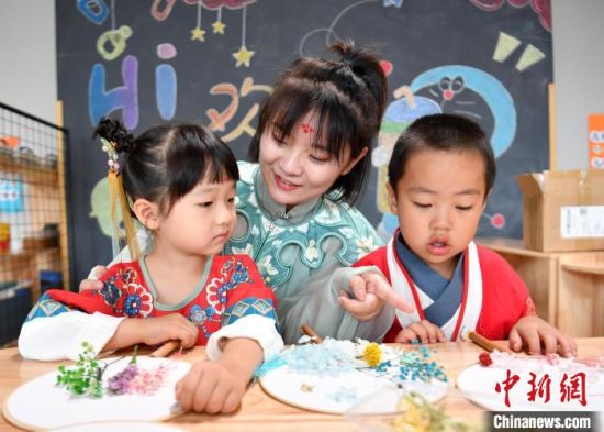 雄安新区容东片区的雄安容和乐安幼儿园里，小朋友们身着中式服装制作团扇。　韩冰 摄