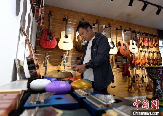 10月7日，游客在周窝音乐小镇的一家乐器商店体验空灵鼓。　苏小立 摄