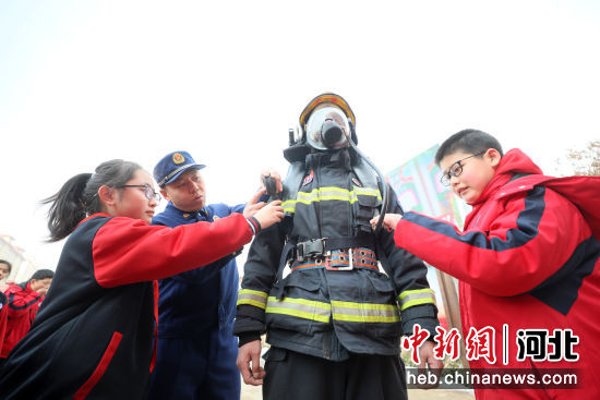 图为在河北省隆尧县第五实验小学，消防员向学生介绍正压式空气呼吸器压力表。 张玲玲 摄