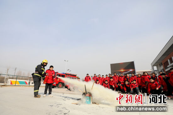 图为在河北省隆尧县第五实验小学，学生在消防员指导下学习使用干粉灭火器灭火。 张玲玲 摄